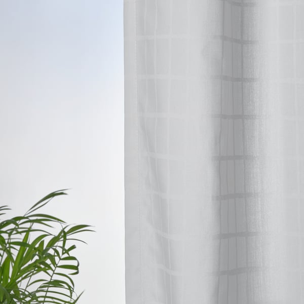 Curtains with grid pattern on window, green plant in front.