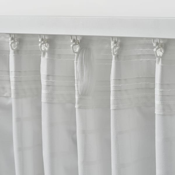 Sheer white curtains with a delicate grid pattern hang from hooks, allowing filtered daylight while providing privacy.
