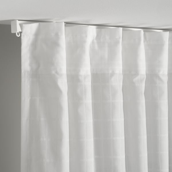 White curtains with subtle grid pattern hang from a white curtain rod, designed to diffuse daylight and offer privacy.