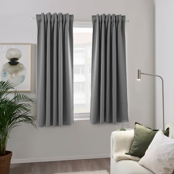 Gray curtains in modern living room with couch, lamp, and plant.
