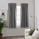 Gray curtains in modern living room with couch, lamp, and plant.
