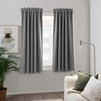 Gray curtains in modern living room with couch, lamp, and plant.