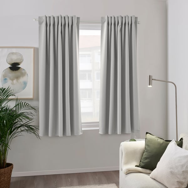 Gray recycled polyester curtain blocks light by window, with couch & lamp.