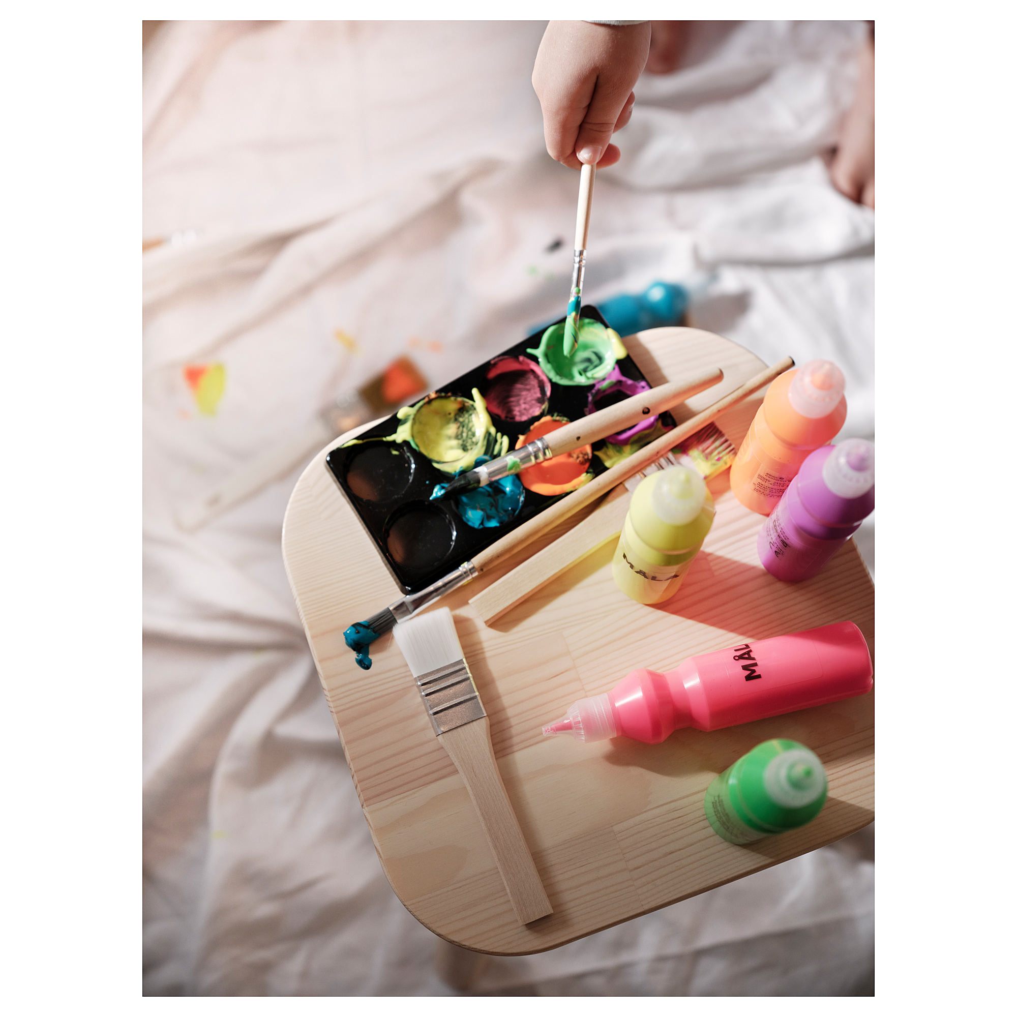 Painting setup: wooden pallet with colorful paints, brushes, childs hand painting.