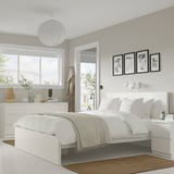 Modern bedroom with MALM bed, clean lines, bedside tables, chest, photos, rug, plants, large window.