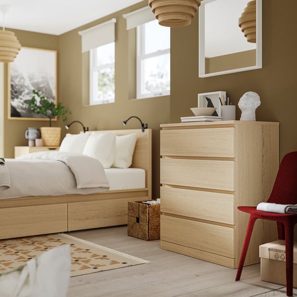 Modern bedrooms feature light wood MALM chest, red chair, bed, rug, and light fixtures.