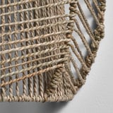 Hand-woven wall lamp with intricate natural texture, emitting a warm glow through sedge gaps, mounted on a smooth wall.