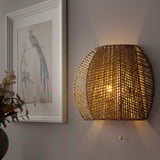 Woven wall lamp illuminates warmly, casting light in multiple directions.