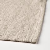 Close-up of beige aprons stitched edge, showcasing its soft, woven cotton-linen fabric.