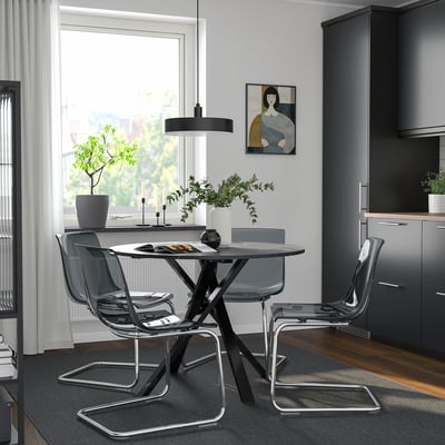Modern dining set with round black table and clear chairs. Minimalist design, size suitable for small spaces.