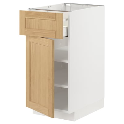 A modern kitchen cabinet, the METOD in white and oak. It open drawers and shelves, displaying a clean, minimalist design.