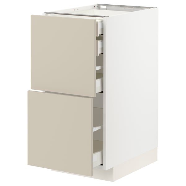 A white METOD kitchen cabinet with beige drawers. Its rectangular with two drawers slightly open, revealing organized interiors.