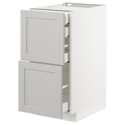 A white METOD kitchen cabinet with light gray lerhyttan fronts and beveled edges, featuring self-closing drawers.