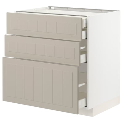 A white METOD kitchen cabinet with beige drawers, designed for storage with a sleek, modern look.