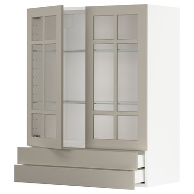 A beige METOD kitchen cabinet with glass doors and drawers, featuring a modern design and adjustable shelving.