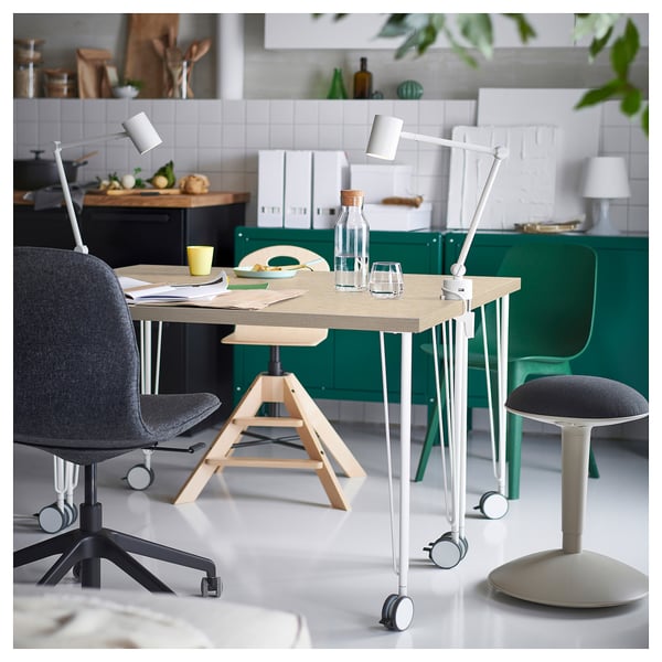 Modern desk with adjustable lamps, grey chair, in green-white kitchen.