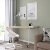 Home office with MITTCIRKEL desk, chair, lamp, and posters. Light wood desk, white chair, zebra poster.