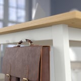 Brown leather bag hangs on high tables hook, designed for standing or sitting.