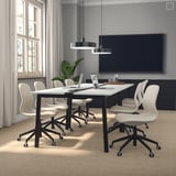 Modern conference room with MITTZON table, gray swivel chairs, black lamp, tv, and window with white curtains.