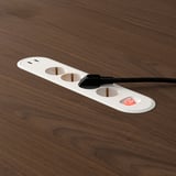 MITTZON power outlet on wood table, featuring three usb ports and a switch.