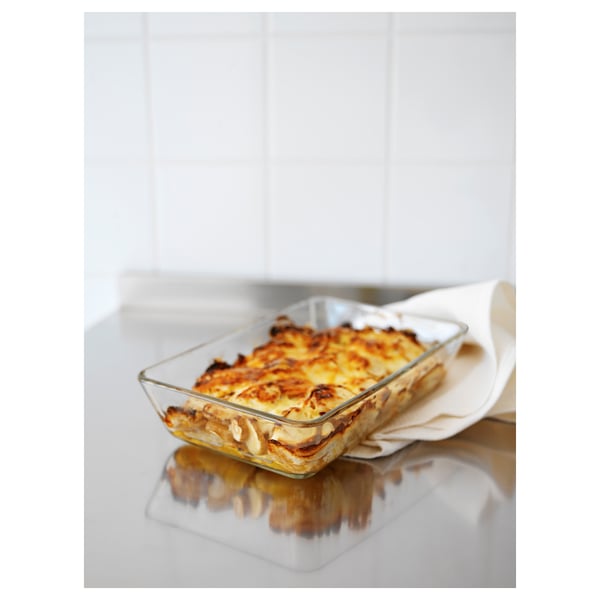 Clear glass oven dish with golden-brown baked food. Used on a white surface. Suitable for microwave, oven, and dishwasher.