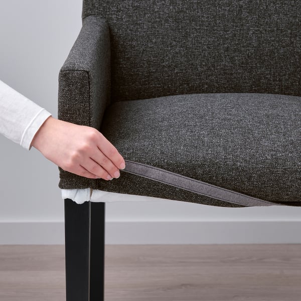 Person adjusting cover on grey MÖRBYLÅNGA chair. Easy-to-remove and washable.