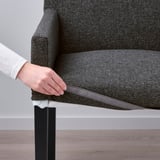 Person adjusting cover on grey MÖRBYLÅNGA chair. Easy-to-remove and washable.
