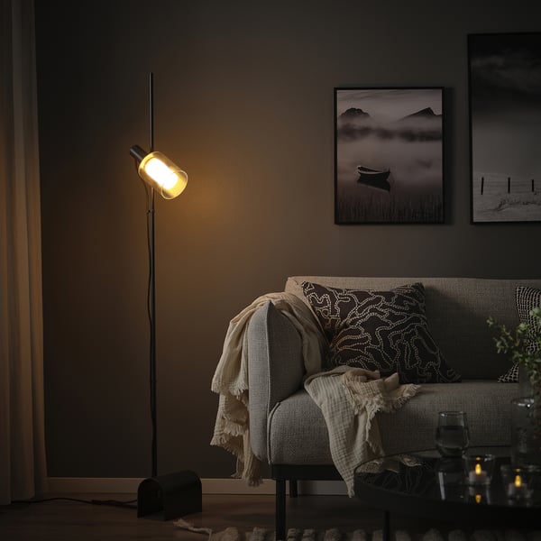 Cozy living room with MOLNART lamp, sofa, & black-and-white photos.