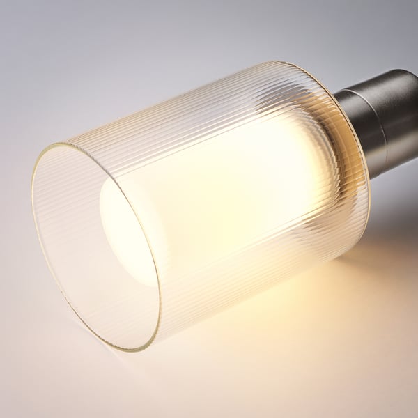 A close-up of a ribbed glass lampshade glowing warmly, showing detailed patterns, highlighting quality design.