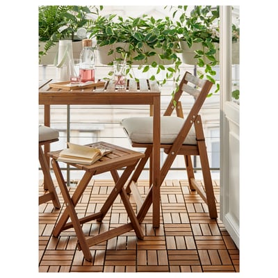Wooden balcony set with light cushions, plants, and books.