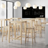 Modern café with light wooden stools, hanging lights, and chalkboard menu.
