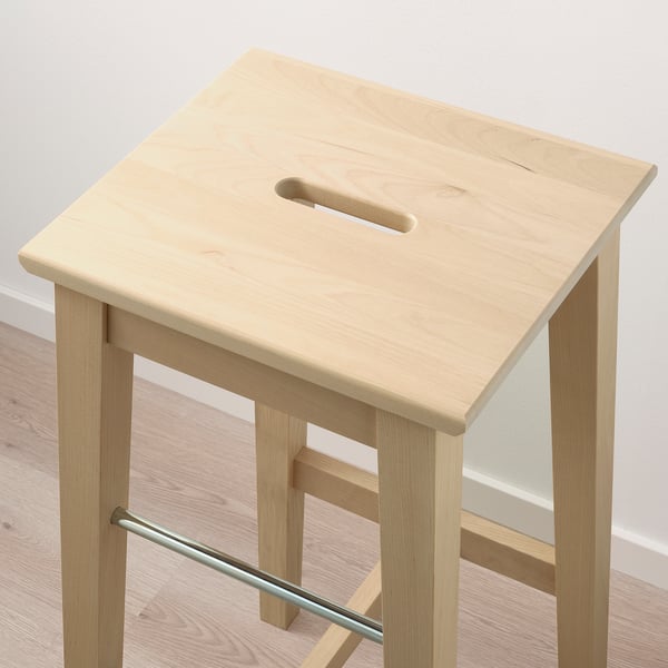 Wooden stool with metal footrest, sturdy birch legs, smooth finish.