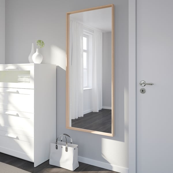 Mirror on door reflects room. Beside it, bag and vase on dresser.