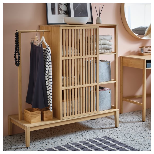NORDKISA light wood storage unit with clothes and decor.