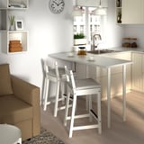 Small modern kitchen with white chairs and counter.