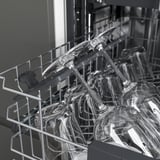 Open dishwasher: silverware top, glasses bottom, organized.