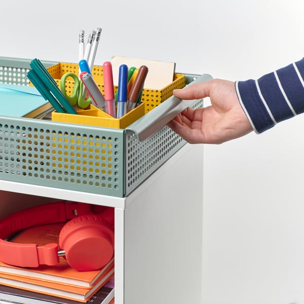 A person pulling a storage trolley containing school supplies.