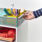 A person pulling a storage trolley containing school supplies.