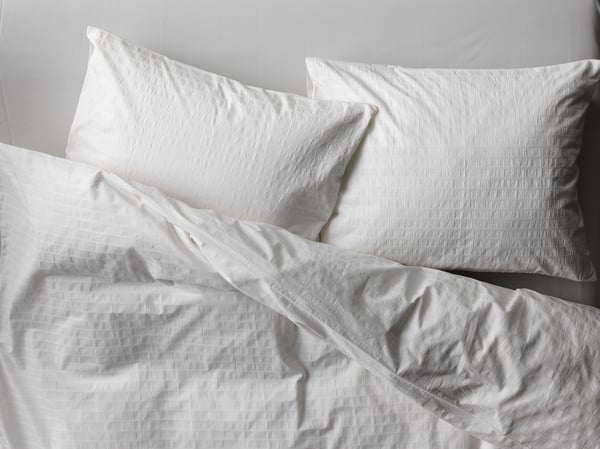 White bedding set with textured, crisp duvet and pillows, made of 100% cotton.