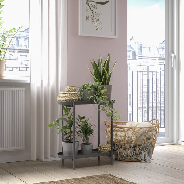 OLIVBLAD plant stand with three shelves and potted plants near windows and cozy rug, wicker basket, and radiator.