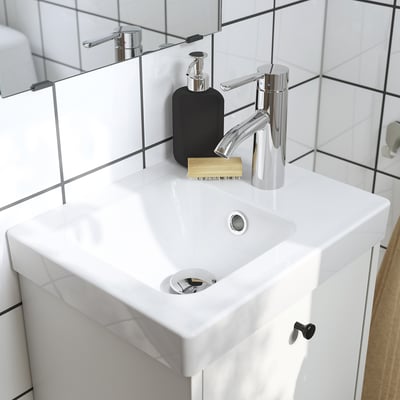 Modern bathroom sink with chrome faucet and accessories on counter.