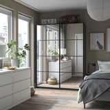 Modern bedroom PAX wardrobe with glass doors, gray decor, and wooden floor.