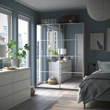 Modern bedroom with PAX wardrobes, sliding glass doors, gray walls, plants, and a large window.