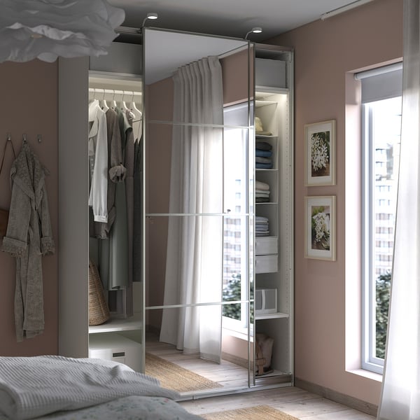 Bedroom with modern wardrobe, mirrored sliding doors, hanging clothes, shelves, and large window.