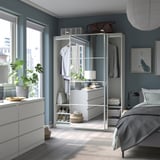 Modern white bedroom with PAX wardrobe, mirror, dresser, plants, & gray bedding