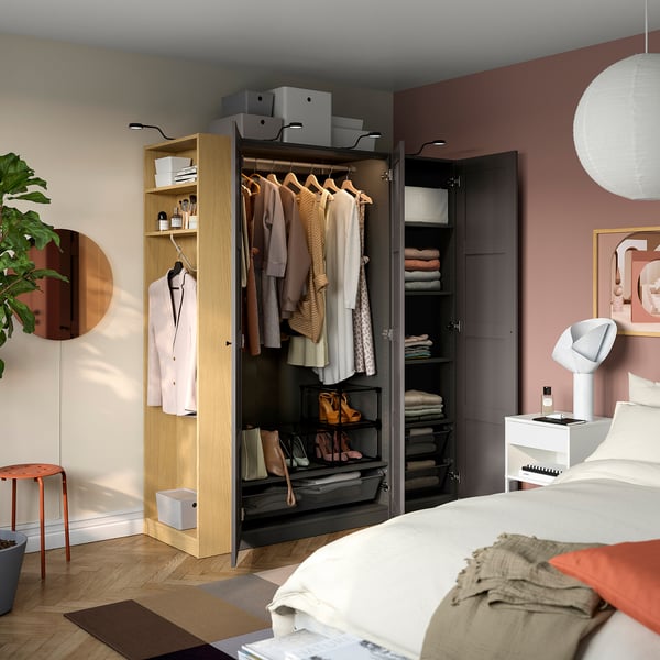 Bedroom with an open PAX wardrobe showing clothes, shelves, and storage boxes.