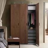 Open wooden wardrobe revealing clothes, shelves, and drawers. Interior lighting highlights organized storage.