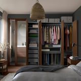 Organized bedroom closet with clothes, shelves, drawers, lamp, and flowers.