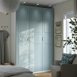 Bedroom with large blue PAX wardrobe, floral sofa, pendant lamp, and natural light.