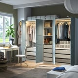 Modern bedroom with PAX wardrobe, open doors showing clothes and storage, integrated lighting.